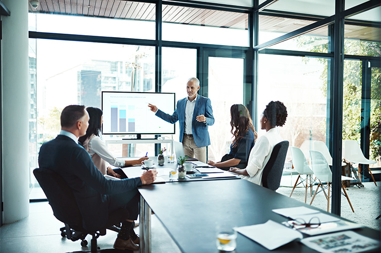 A man presenting data in front of a group in an office