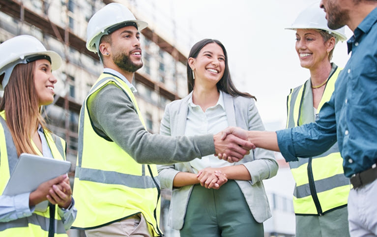 A team on a construction site smiling at each other. 