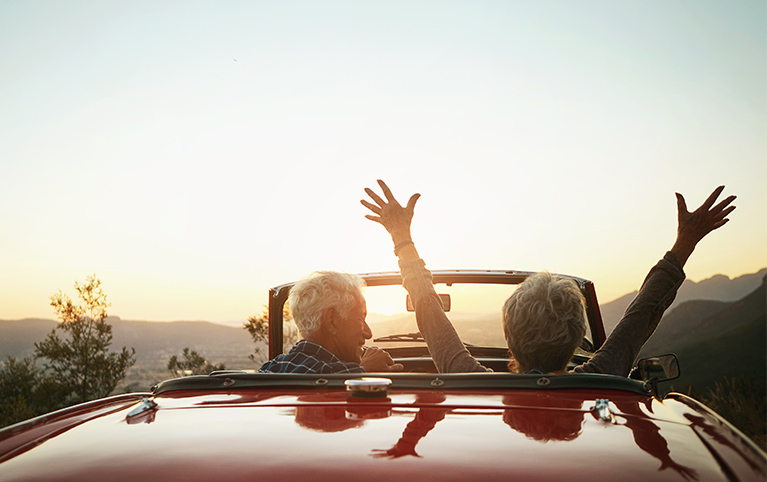 Image of an old couple driving into the sunset post retirement. 
