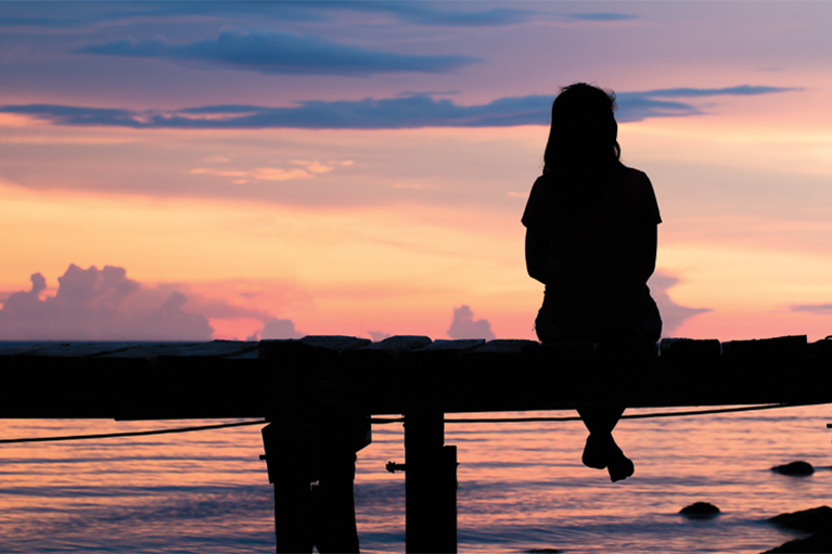 Woman looking to the horizon at sunset.