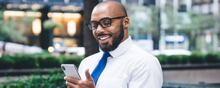 A man in glasses reading something on his mobile phone