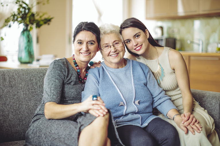 A grandmother, mother and daughter sitting in their home representing women’s generational wealth.