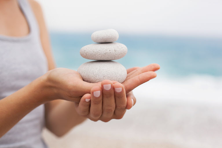 A woman holding three stones in her palm representing a balanced investment strategy.