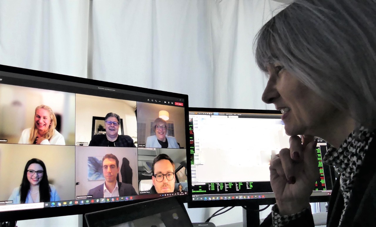 A woman watching a conference on a screen.