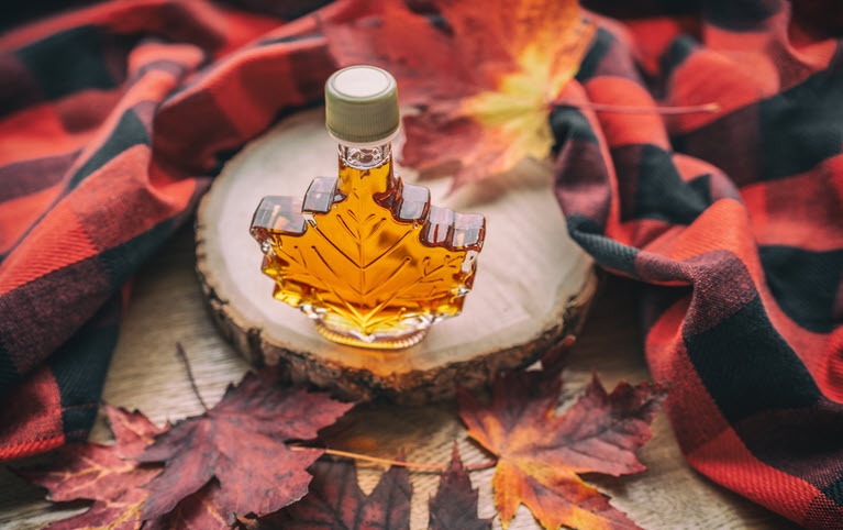 a maple syrup on red leaves surrounded by a red and black plaid