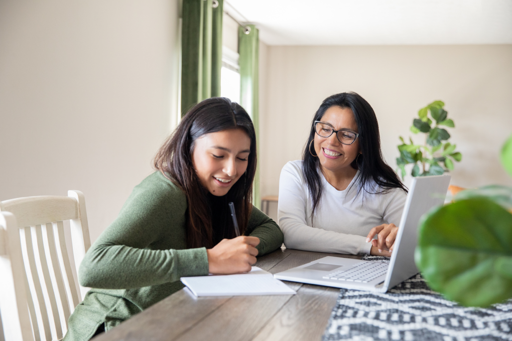 Photo of a parent and their child talking about money at a table 