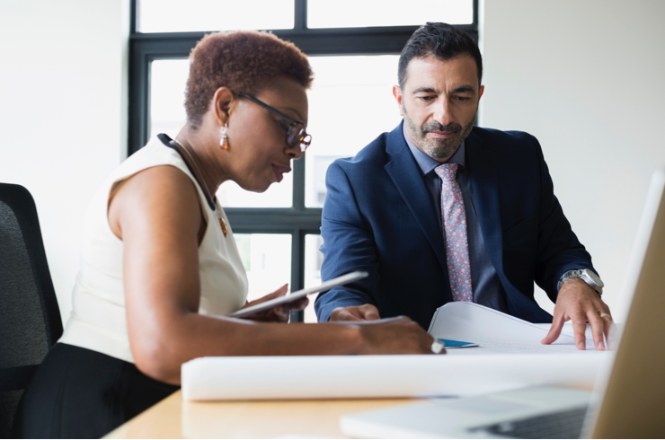 Two advisors around age 40 analyze paper reports in an office