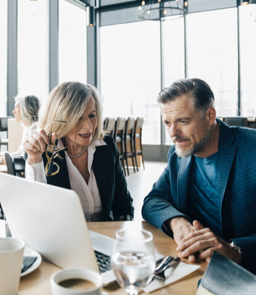 Conseillère en placement, l'air serein, qui lit avec son client des informations financières sur un ordinateur portable.
